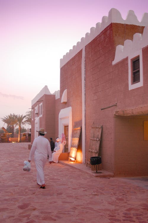 Man in White Thobe Walking Near the Building at Daytime