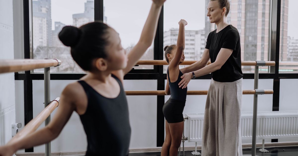 Dance teacher demonstrating a move to children in a bright studio