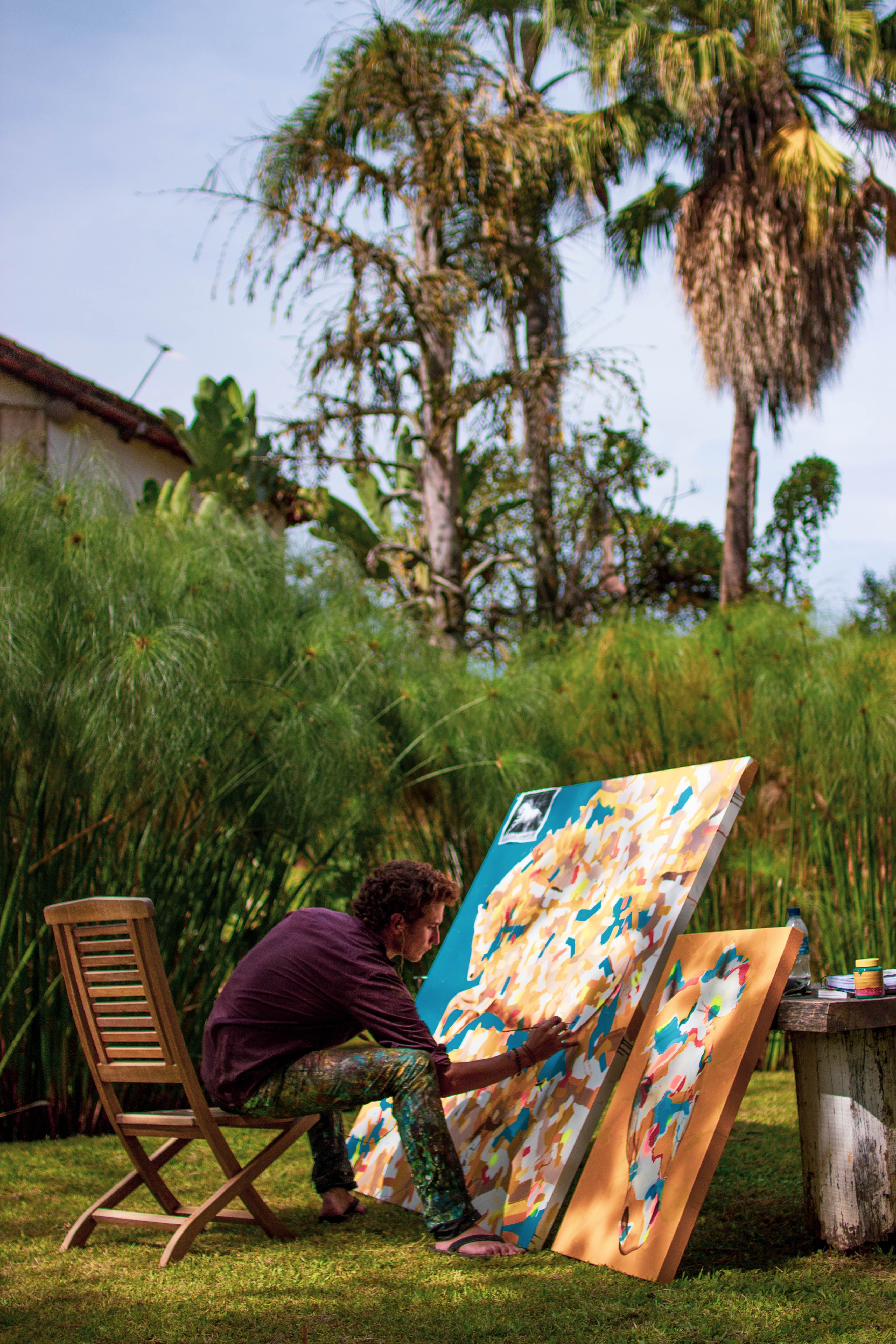 Artist painting on a large canvas outdoors in Tiradentes, Brazil. Vibrant and creative setting.