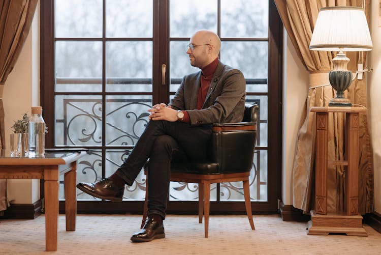 Man In Black Suit Sitting On A Chair 