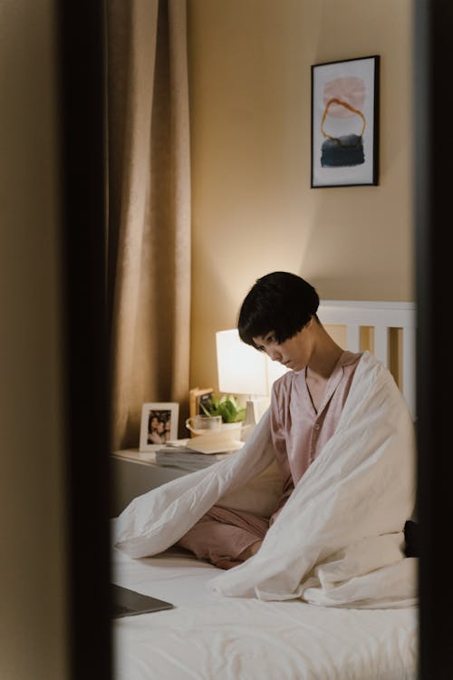 Woman in Pajama Sitting on Bed