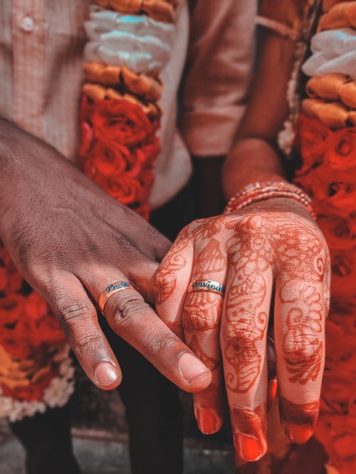Free Close-up of a couple's hands with henna and wedding rings, symbolizing love and tradition. Stock Photo