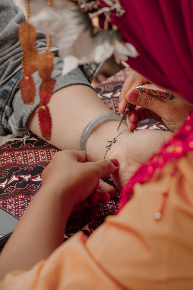 Artist Applying Henna Tattoo On Person