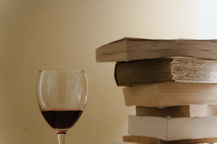 Glass Of Red Wine Beside A Stack Of Books