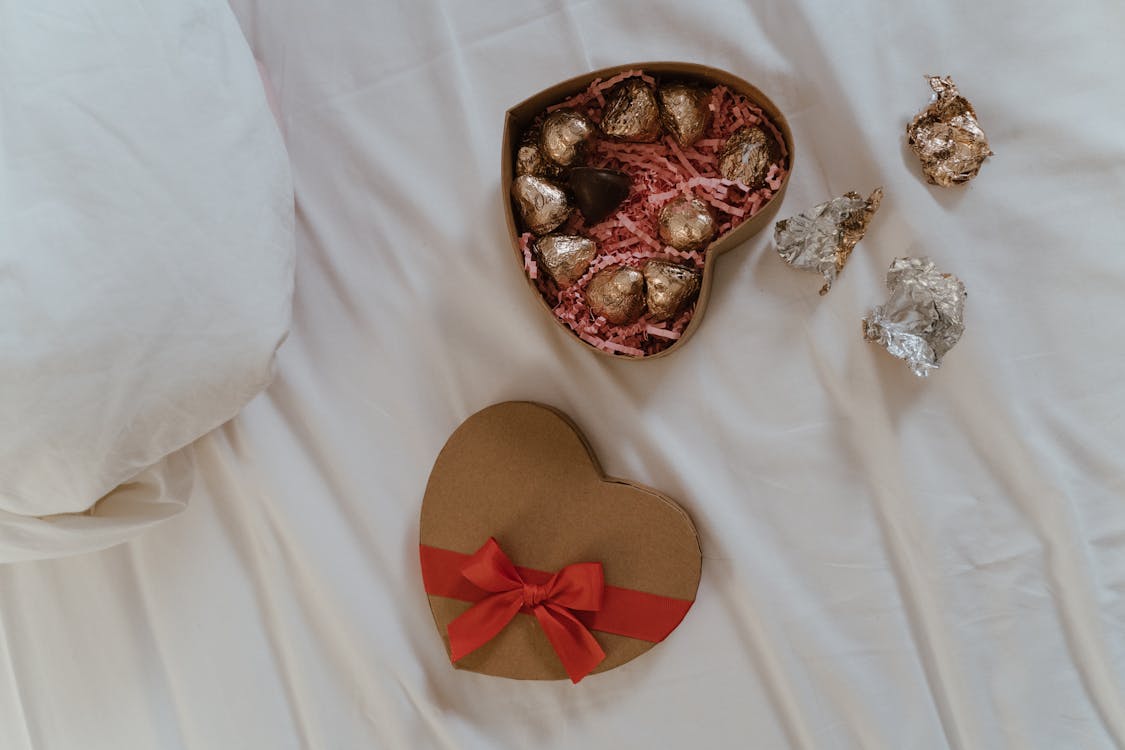 Free Heart Shaped Box of Chocolate Candies on White Linen Stock Photo