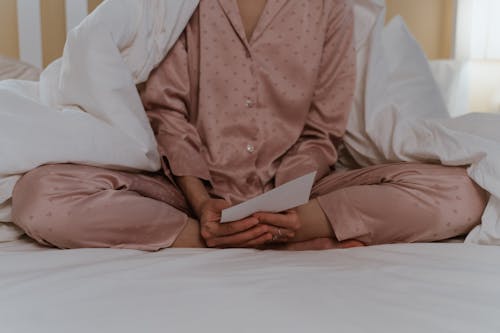 Person Sitting on Bed Holding a Letter