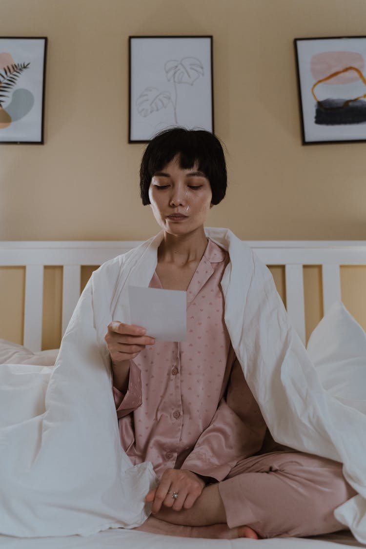 Woman Sitting On Bed Reading A Letter