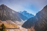 白雪皑皑的山脉下，蜿蜒的河流在蓝天的映衬下，景色壮丽