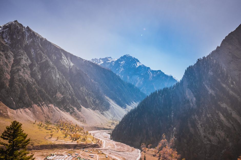 Stunning view of snow-capped mountains with a meandering river under a blue sky.