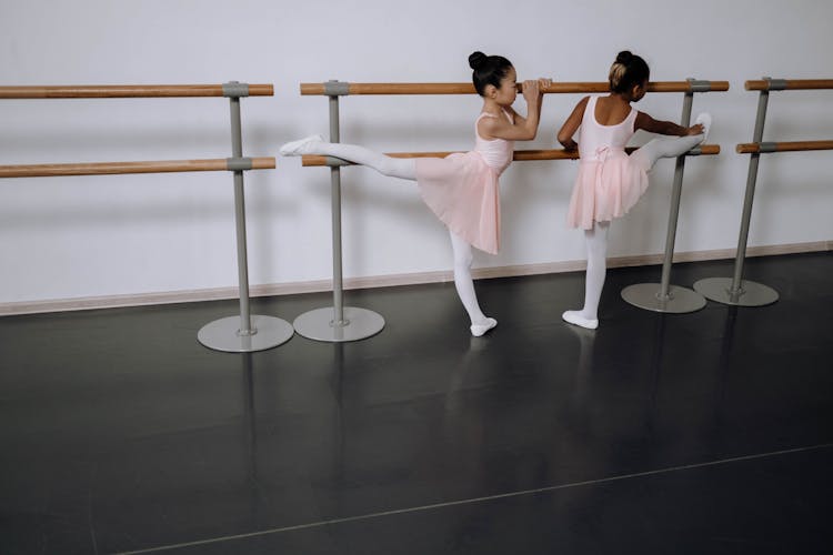 Young Ballerinas Stretching On A Barre