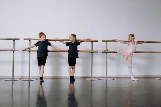 Three children practicing ballet at a studio with focus on grace and skill.