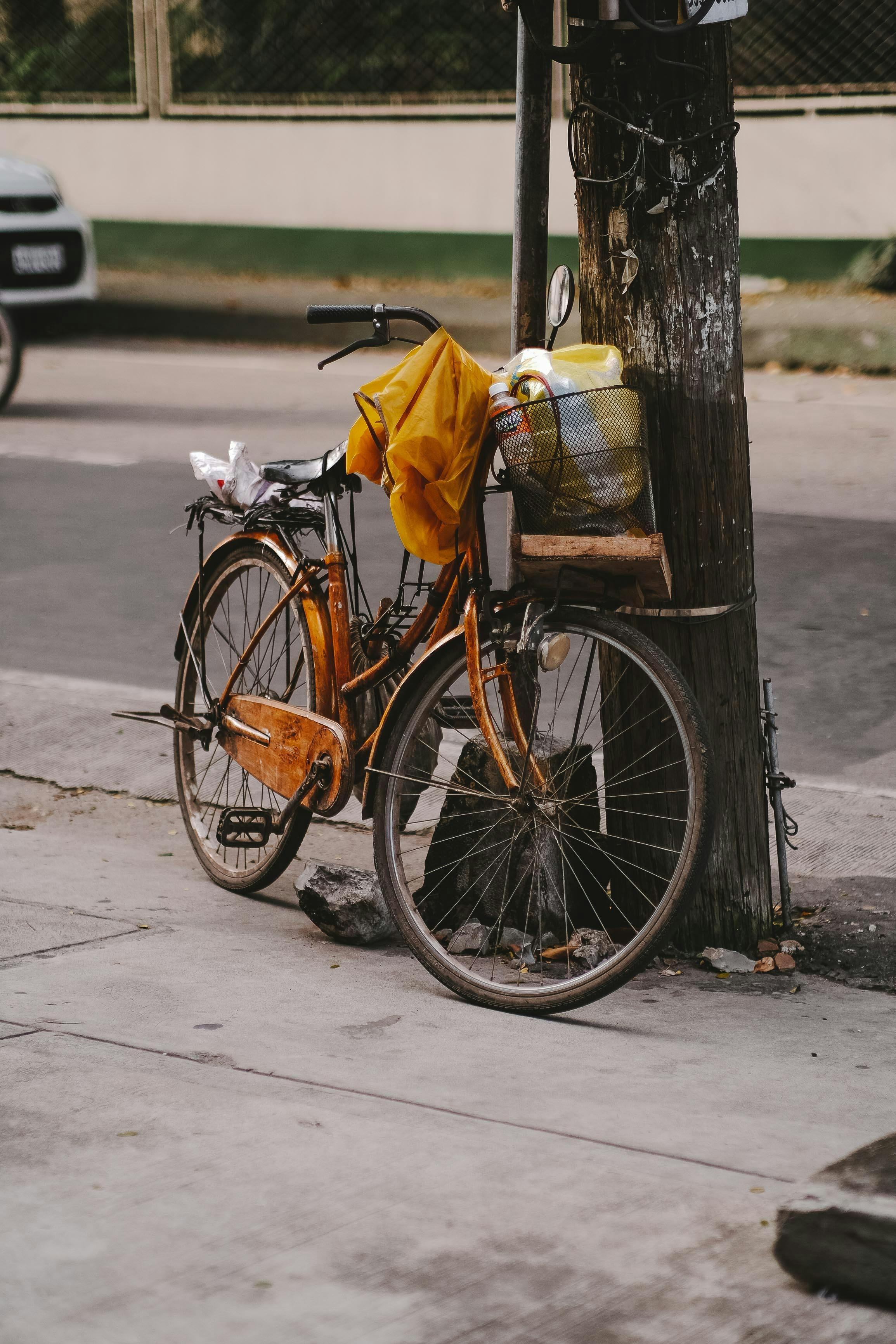 Free A quaint, rustic bicycle parked on a street against an old wooden post. Stock Photo