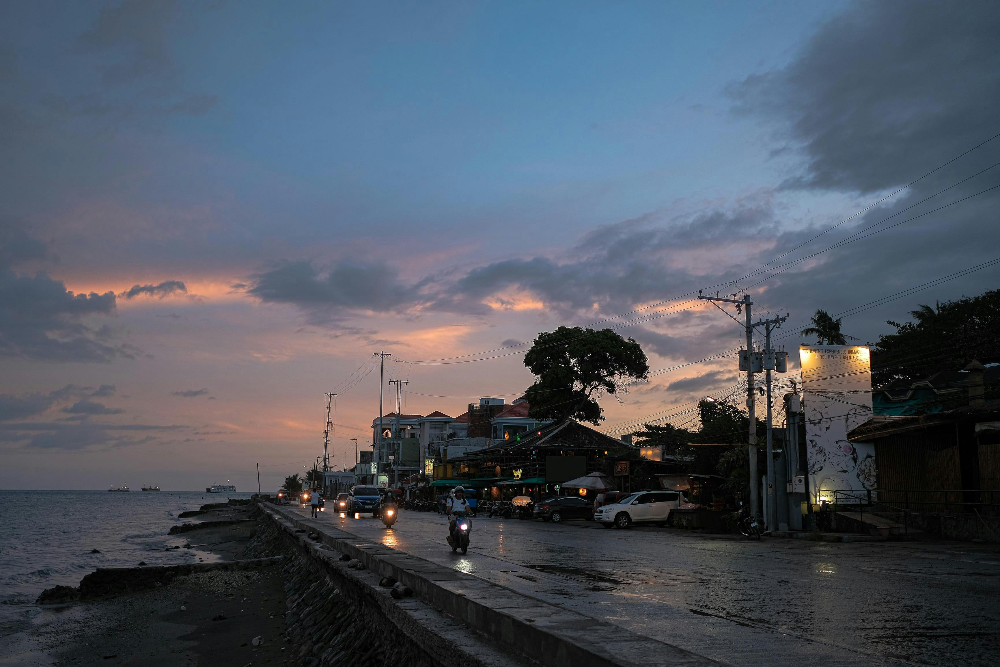 People Riding on Scooters and in Driving Cars on a Seashore Road · Free
