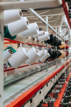 Detailed view of yarn spools in a textile factory, showcasing industrial equipment.