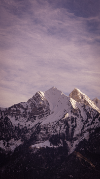 Stunning view of the snow-capped peaks in Walenstadt, Switzerland, under a cloudy sky.