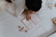 A Person Reading a Notebook while Lying on a Bed