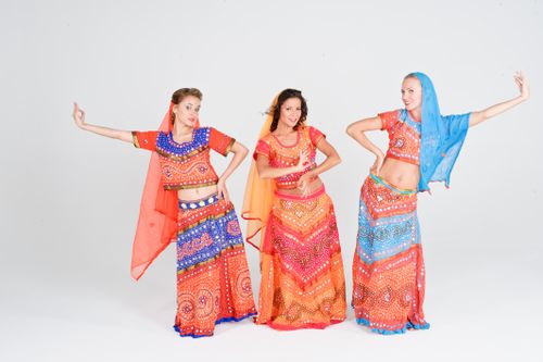 Free Three women in vibrant traditional dance costumes posing with expressive gestures in a studio. Stock Photo