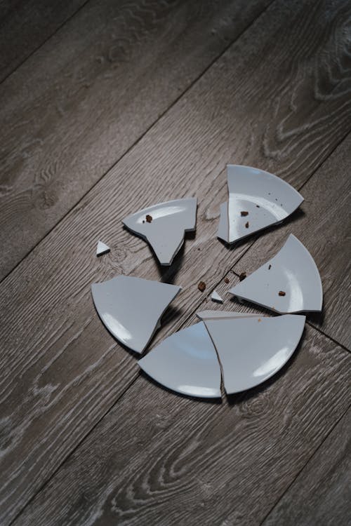 Free Close-Up Shot of Shards of a Broken Ceramic Plate on a Wooden Surface Stock Photo