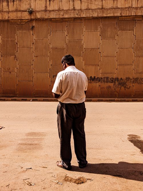 Free Back view of anonymous black male in casual clothes standing on street near old building in city Stock Photo