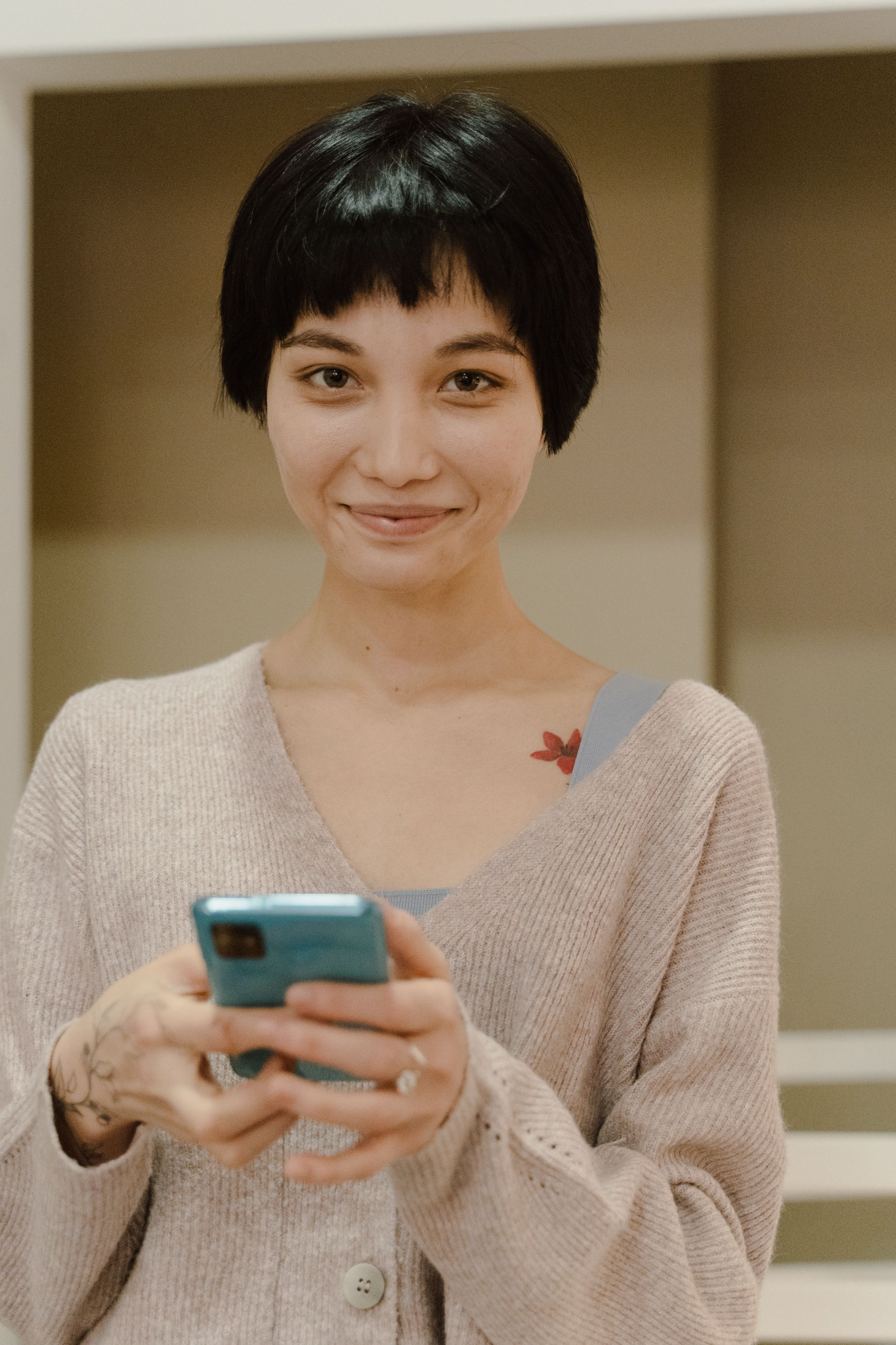 A short haired woman smiling while holding her cellphone