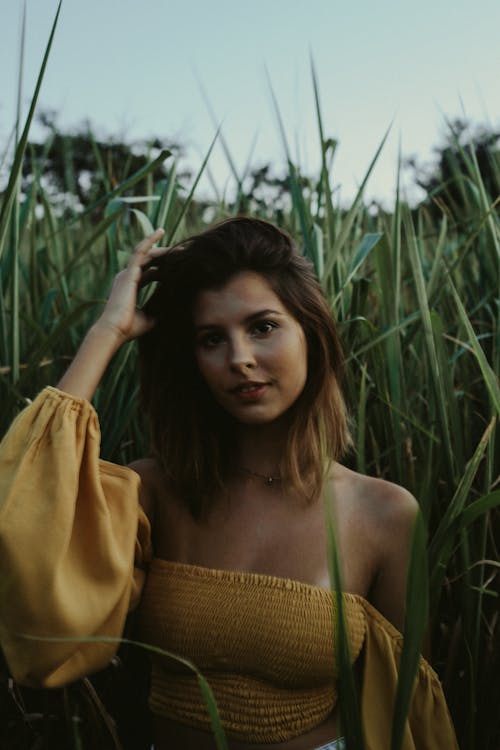 Free Woman in a Yellow Off Shoulder Shirt Touching Her Hair while Looking at the Camera Stock Photo