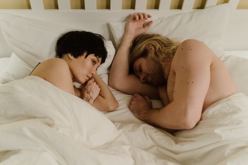 Free A serene scene of a couple intimately resting together in bed, conveying tenderness and connection. Stock Photo