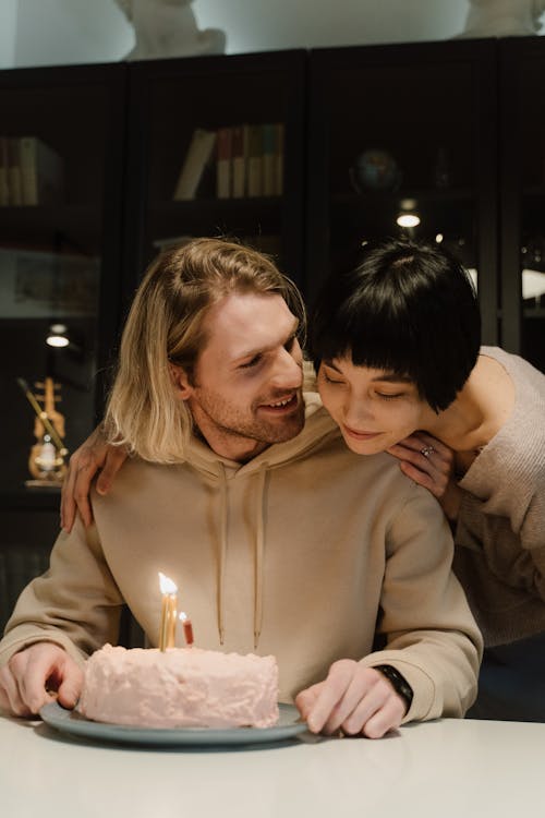 Free Man in Beige Hoodie Sitting at Table with Birthday Cake Stock Photo