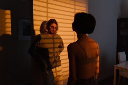 Free Two adults in a room with striped shadow patterns on the wall at sunset. Stock Photo