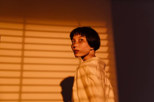 A Woman in White Long Sleeves Near a White Wall