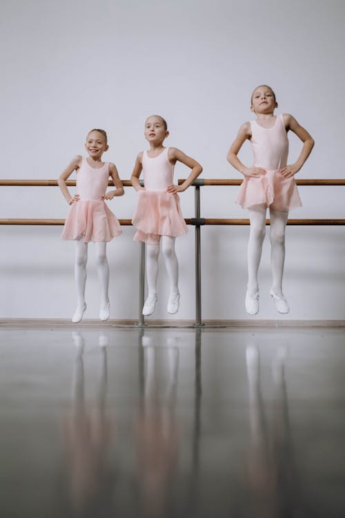 Free Three Little Girls in Pink Leotards Jumping Stock Photo