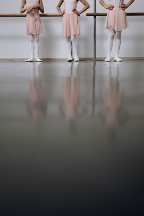 Free Three young ballet dancers practicing in a studio with reflections on the floor. Stock Photo