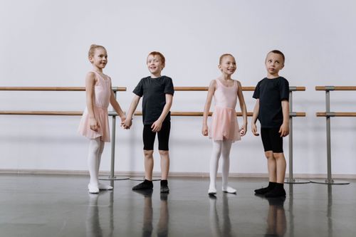 Free Four young children in ballet attire practice dance in a bright studio setting. Stock Photo