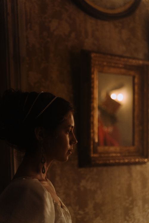 Free An elegant woman stands in an art gallery, reflecting in a framed mirror. Stock Photo