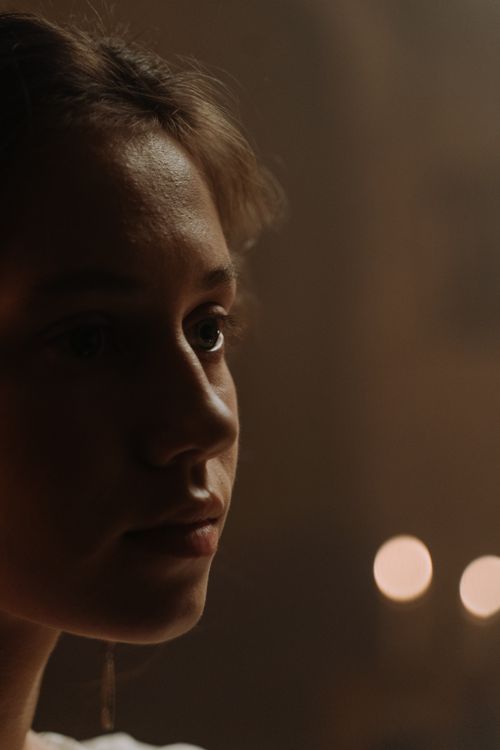 Free Close-up of a woman in a dimly lit setting with bokeh lights. Stock Photo
