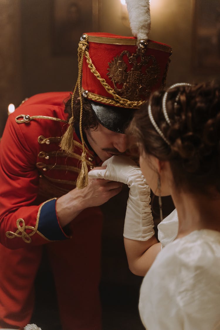 Man In Scarlet Tunic Kissing The Hand Of A Woman