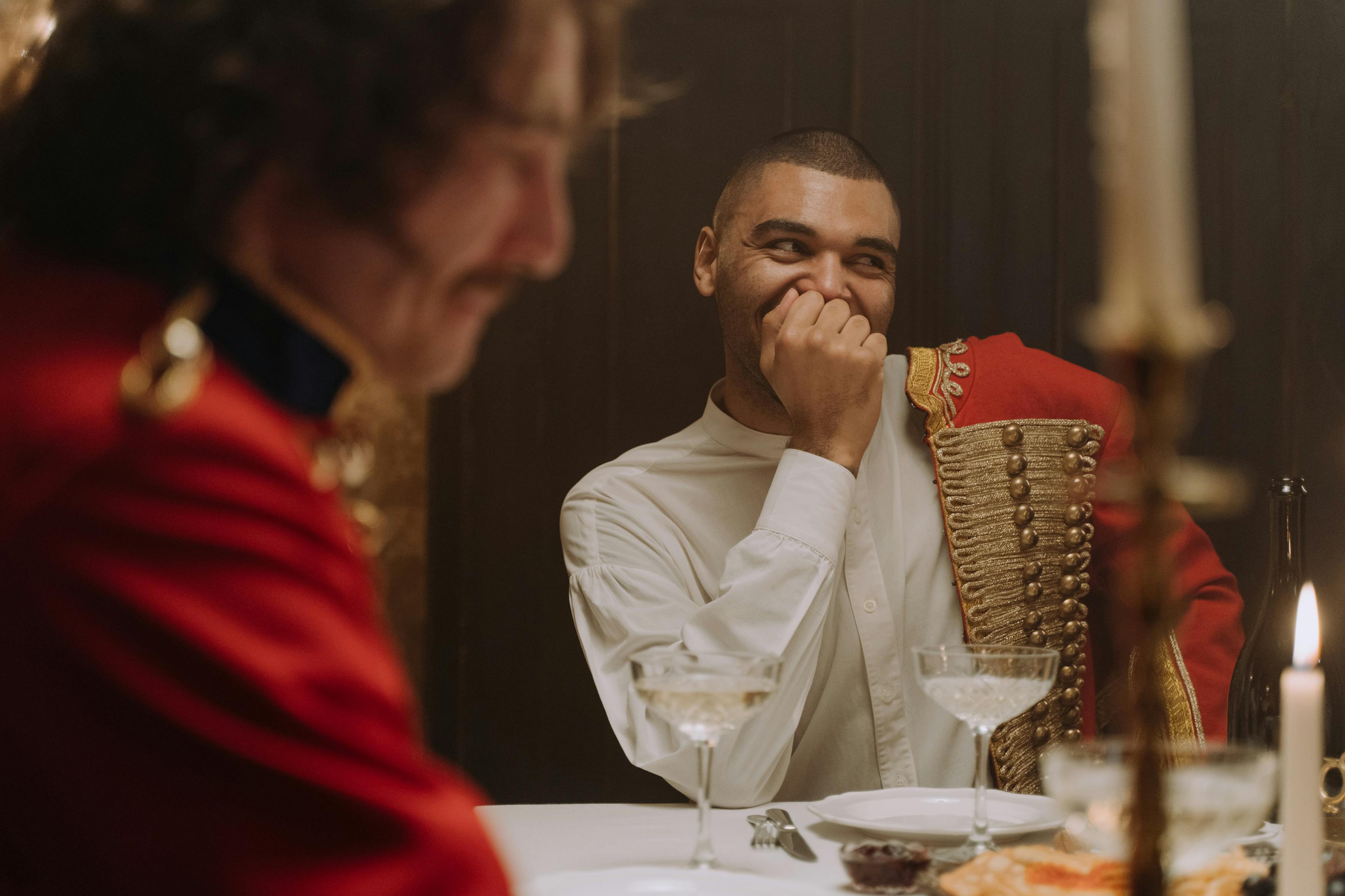 Historical scene of men dining in hussar costumes, exuding elegance with candlelight and uniforms.