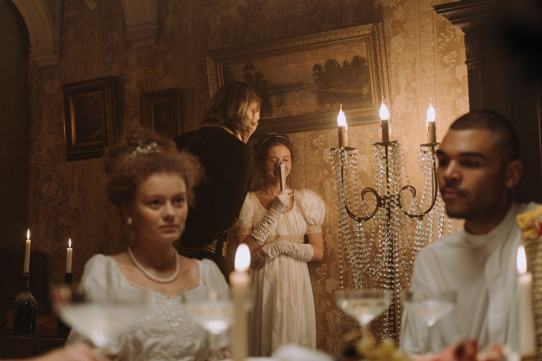 Elegant Victorian-themed dinner with guests in period attire holding a hand fan.