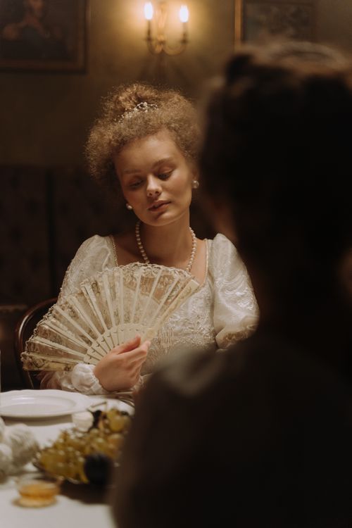 Free A woman in a vintage setting holding a decorative fan, exuding elegance and nostalgia. Stock Photo