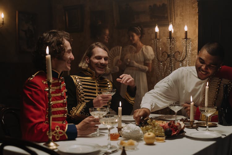 Men In British Military Costumes Sitting By The Table Having A Feast