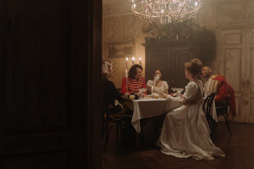 Group of Men and Women in Costumes Sitting by the Table 