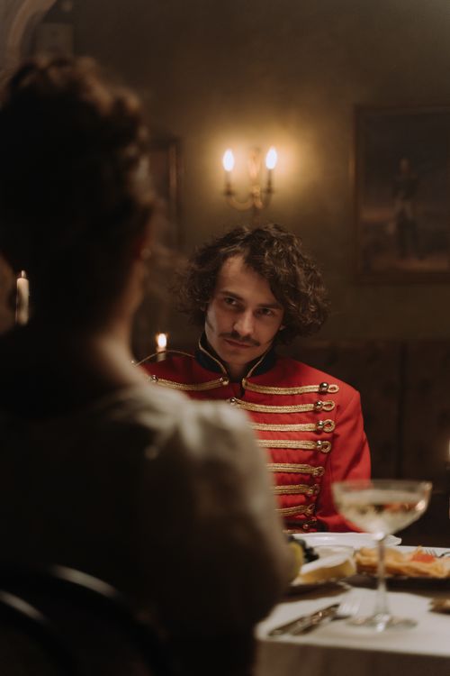 Free A man in historical costume at an elegant dinner party. Candlelit ambiance enhances the aristocratic setting. Stock Photo