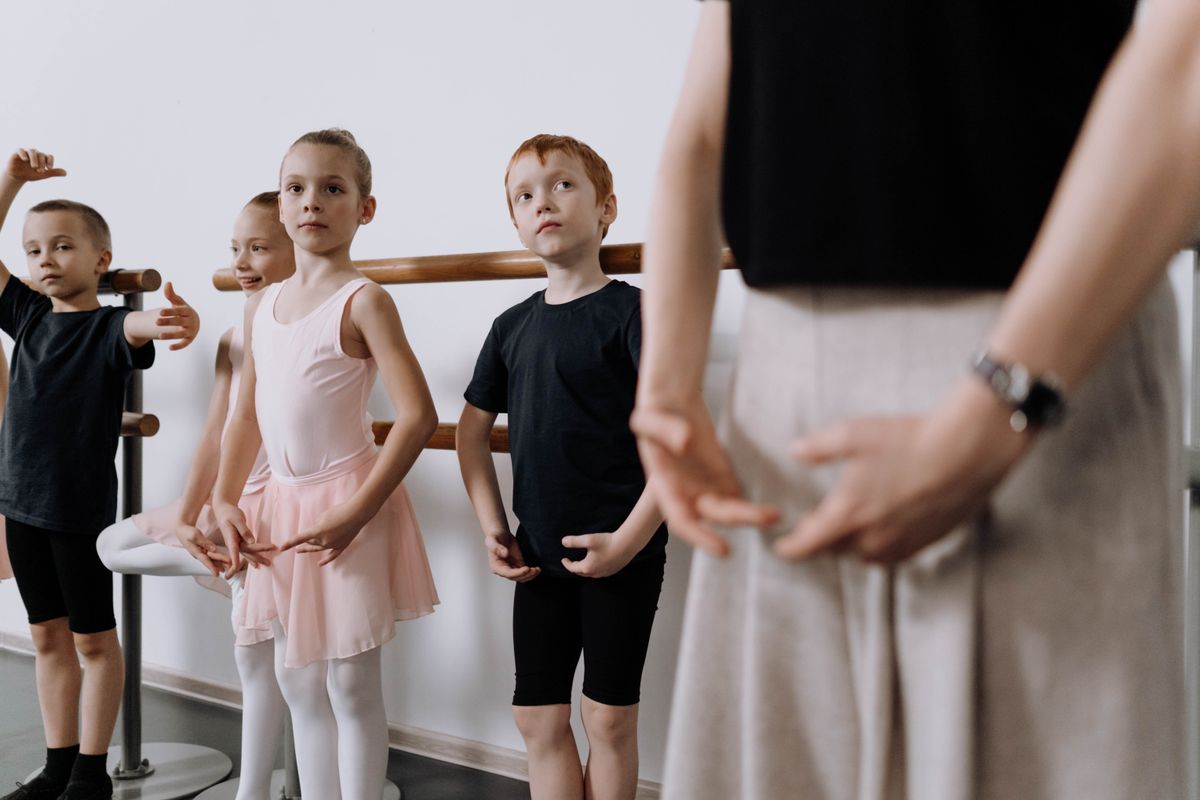 Children learning dance with their instructor in class