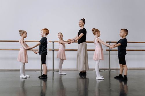 Free Instructor guides children in ballet class, focusing on dance basics. Stock Photo