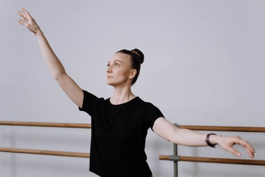 A woman practicing ballet in a studio, capturing elegance and focus in a dance pose.