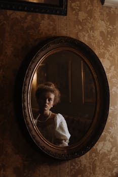 A woman in period attire reflects in a vintage mirror, creating an aristocratic ambiance.