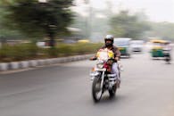 一名戴着头盔的男子骑着摩托车，穿行在繁忙的城市道路上，捕捉着城市生活的动态与活力