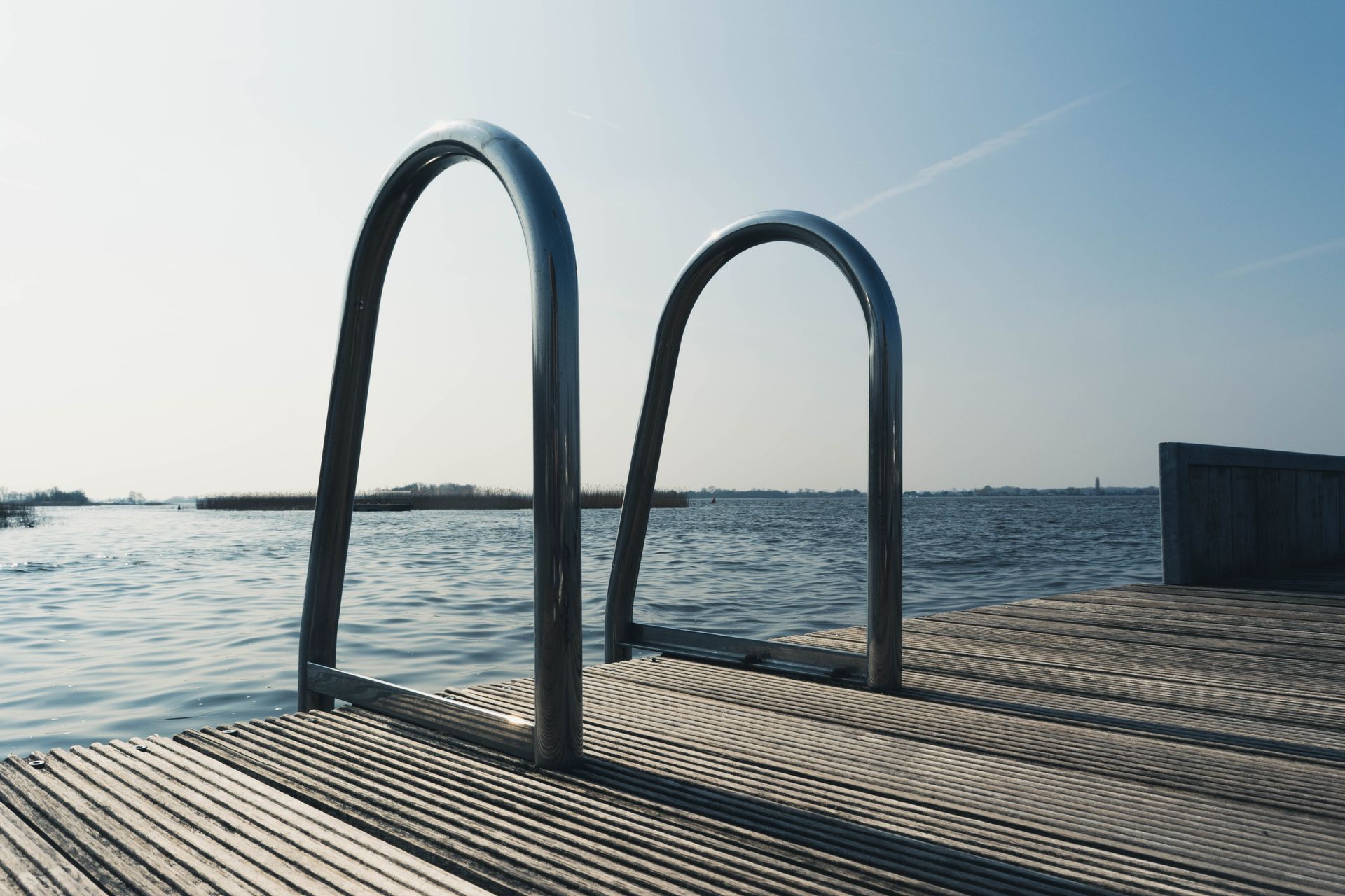 Explore the tranquil beauty of a wooden deck overlooking a serene lake under clear skies.