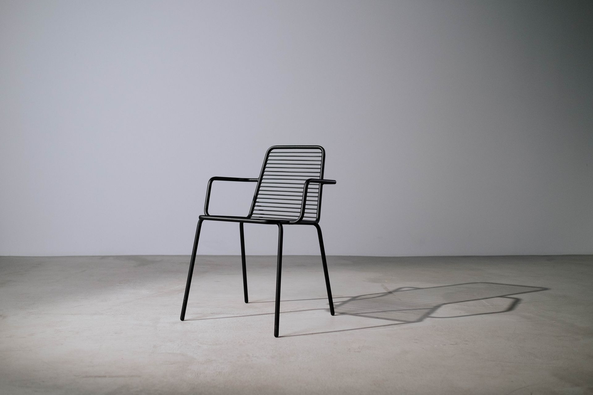 A minimalist metal chair in a studio setting casting a shadow, perfect for design concepts.