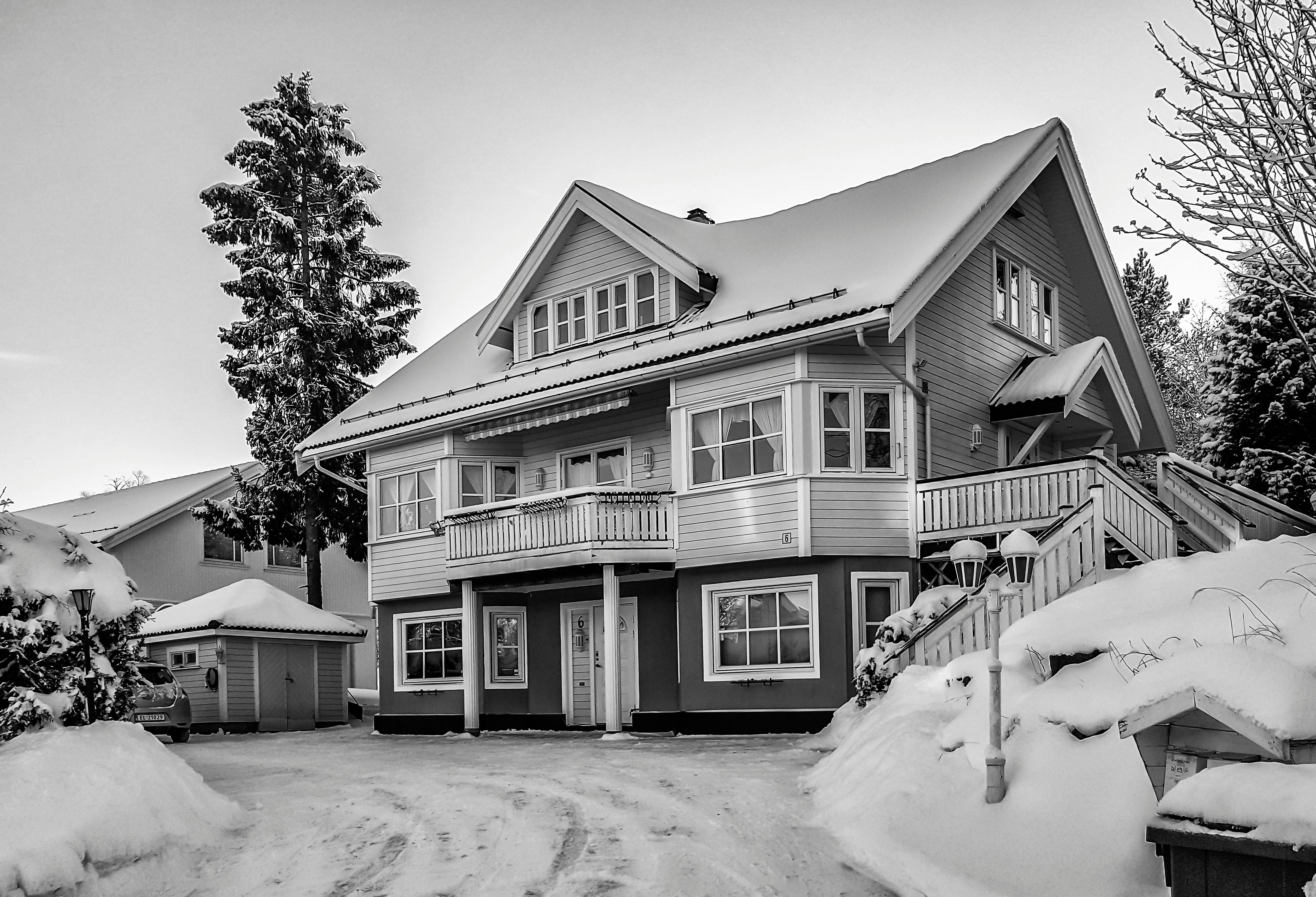 Black and white photo of a snow-covered house showcasing winter architecture and serene landscape.