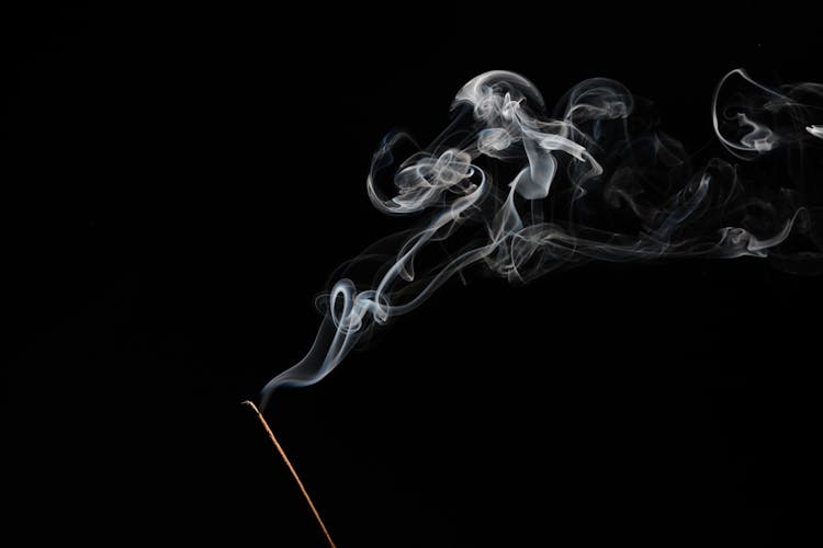 An Incense Stick With Smoke On A Black Background